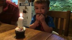 Папа помогает сыну задуть свечу на торте